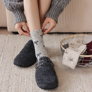 Detail of grey wool socks with blue bow patterns and felt slippers for winter comfort