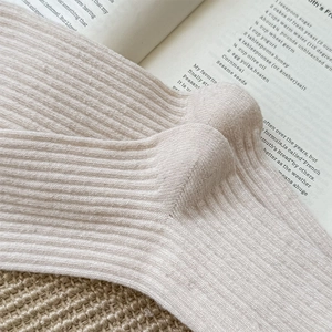 Close-up of beige ribbed knit wool socks showing soft texture and vertical stripe detail