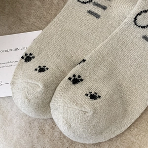 Detailed macro view of waffle-knit wool socks featuring a cute black cat paw print pattern