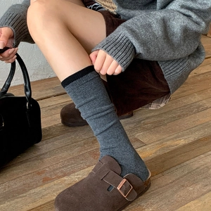 Close-up of thick knit wool socks in dark grey with black trim and slouchy texture