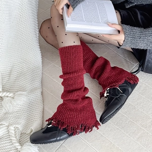 Detail of burgundy knitted leg warmers with vintage fringe hem and vertical ribs