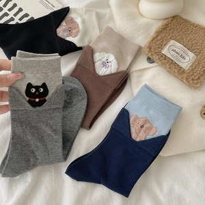 Detail showing five pairs of knitted mid-calf socks with cute cartoon animal embroidery