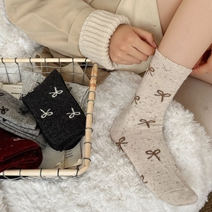 Detail of wool blend socks with knitted bow patterns and warm flecked yarn texture