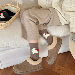 Close-up of cozy winter shoes with faux lamb wool lining and rabbit pattern socks