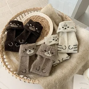 Close-up of cat-themed knitted fingerless gloves in cream and brown wool textures