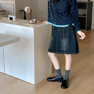 Detail of dark blue denim A-line skirt styled with Tabi shoes and printed crew socks