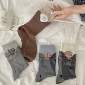 Close-up of cute animal embroidery on neutral-toned cotton crew socks with ribbed cuffs
