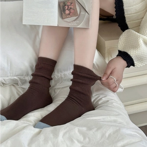 Detailed view of elastic ribbed cuff and blue colorblock heel on brown knit cotton socks