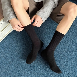 Detail of black ribbed mid-calf sports socks with cotton blend texture on male model