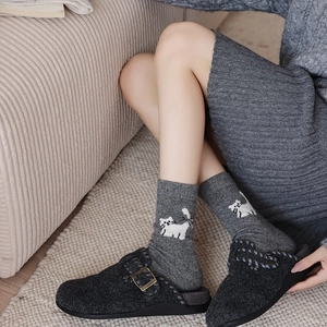 Detail of wool socks with cute white cat pattern worn with gray felt buckle clogs