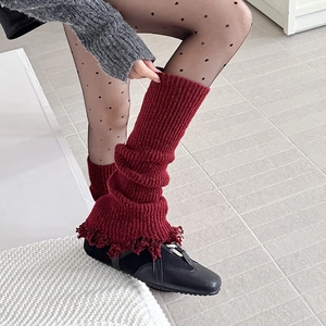 Detail of red knitted leg warmers with vintage fringe edges and textured wave pattern
