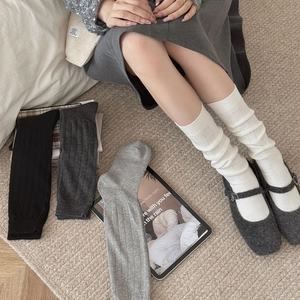 Detailed knit texture of solid white ribbed slouch socks in a cozy home setting