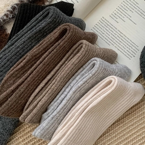 Detailed view of textured rib-knit wool socks in a warm earthy color palette