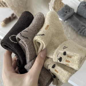 Close-up of thick knitted wool socks with cute cartoon cat embroidery in earthy tones