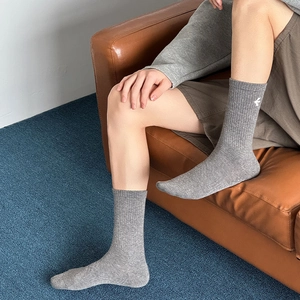 Close-up of grey ribbed cotton socks with white embroidery on a leather sofa
