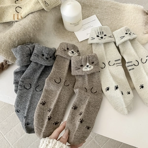 Detailed close-up of three pairs of thick knit wool socks with cute cartoon cat patterns
