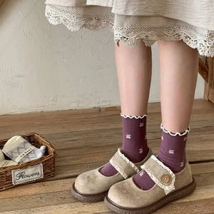 Détail de chaussures Mary Jane en daim beige et chaussettes à broderie cerise