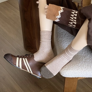 Beige ribbed mid-calf socks paired with brown contrast sneakers in a retro style
