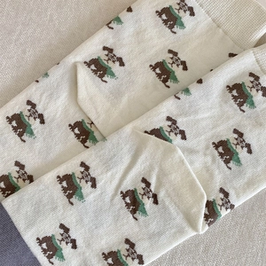 Close-up of cute cartoon puppy jacquard pattern on cream-colored knit crew socks