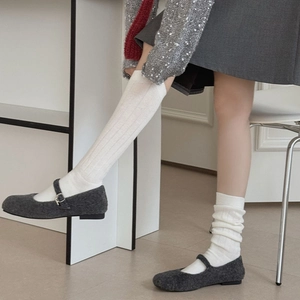 Detail of white ribbed slouch socks paired with grey wool Mary Jane flats on a model