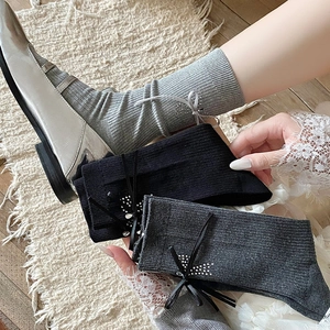 Detail of rib-knit mid-calf socks with delicate rhinestone bows and soft fabric texture