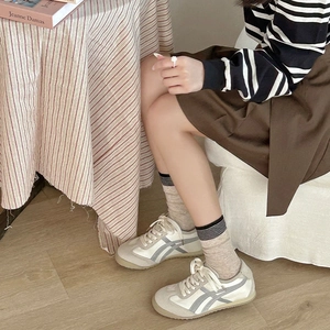 Gros plan de baskets rétro blanc cassé avec rayures grises et chaussettes rayées