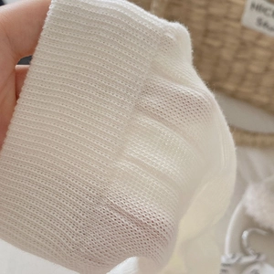 Close-up of white ribbed knit fabric showing elastic texture and soft cotton material