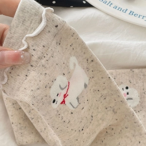 Close-up of ruffled cuff socks with cute cartoon puppy pattern in beige knit texture