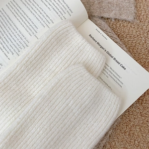 Close-up of cream knit leg warmer showing thick ribbed texture and soft woven pattern