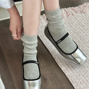 Silver square-toe Mary Jane shoes with black elastic strap and grey knit slouch socks