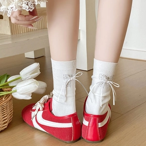 Detail of white ribbed mid-tube sock with a delicate rhinestone bow and ribbon accent