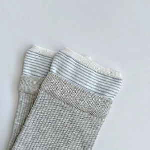 Détail de chaussettes en tricot côtelé avec revers rayé bleu et blanc en gris