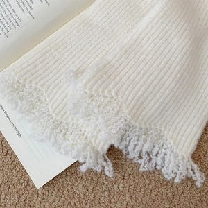 Detailed close-up of white ribbed knit fabric with unique curly fringe edges