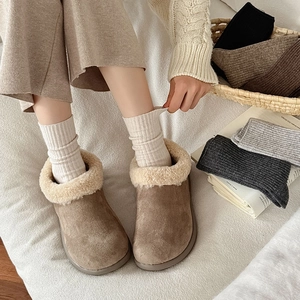 Close-up of cozy light brown suede snow boots with thick white faux fur lining for winter