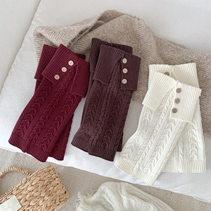 Detail of cable knit leg warmers in three colors with decorative wooden buttons