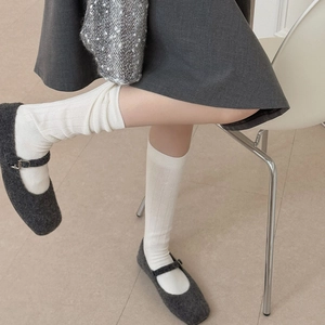 Detailed texture of off-white ribbed cotton mid-calf socks worn with Mary Jane shoes