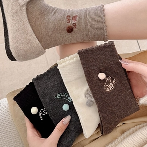 Detailaufnahme von gerippten Socken mit Plüschpompons und niedlicher Katzenstickerei