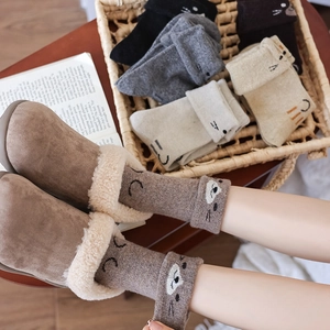 Detail of cartoon cat wool socks paired with plush-lined winter slippers in cozy home setting
