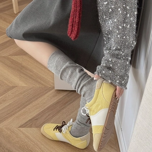 Detail of yellow and beige leather sneakers with textured rubber sole on wooden floor
