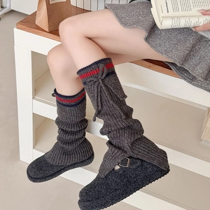 Detail of dark grey ribbed leg warmers with sporty stripes and bow tie accents