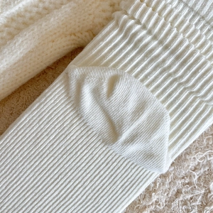 Close-up of cream vertical ribbed knit fabric showing soft texture and elastic weave