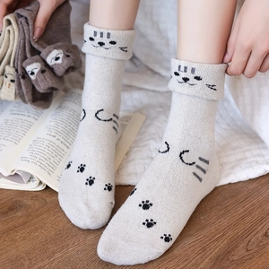 Detail of warm wool knit socks with cute cartoon cat face and paw prints design