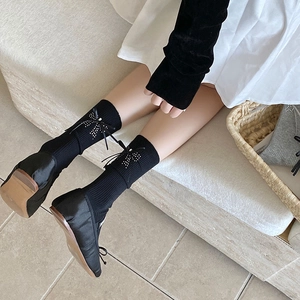 Detail of black knit crew socks with white polka dot bow and black ribbon bow accent