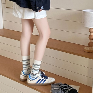 Détail de chaussettes rayées en cachemire avec étiquette et baskets bleues