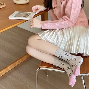 Detailed knit texture of light grey socks with cute dog prints and pink heel accents