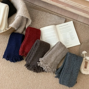 Flat lay of colorful ribbed knit leg warmers with tassel details on cozy rug