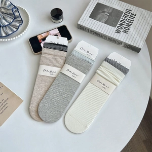 Texture de maille détaillée de trois paires de chaussettes rayées en beige, gris et blanc