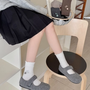 Detail von Strick-Socken mit Cartoon-Stickerei, Wellenbündchen und süßen Pompon-Akzenten