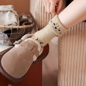 Close-up of warm brown mule slippers with wool lining and cute cartoon cat motif socks