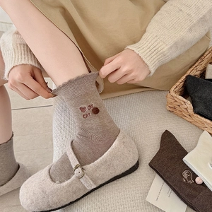 Detail der süßen Katzenstickerei und Rüschenmanschette an braunen Socken im Japan-Stil